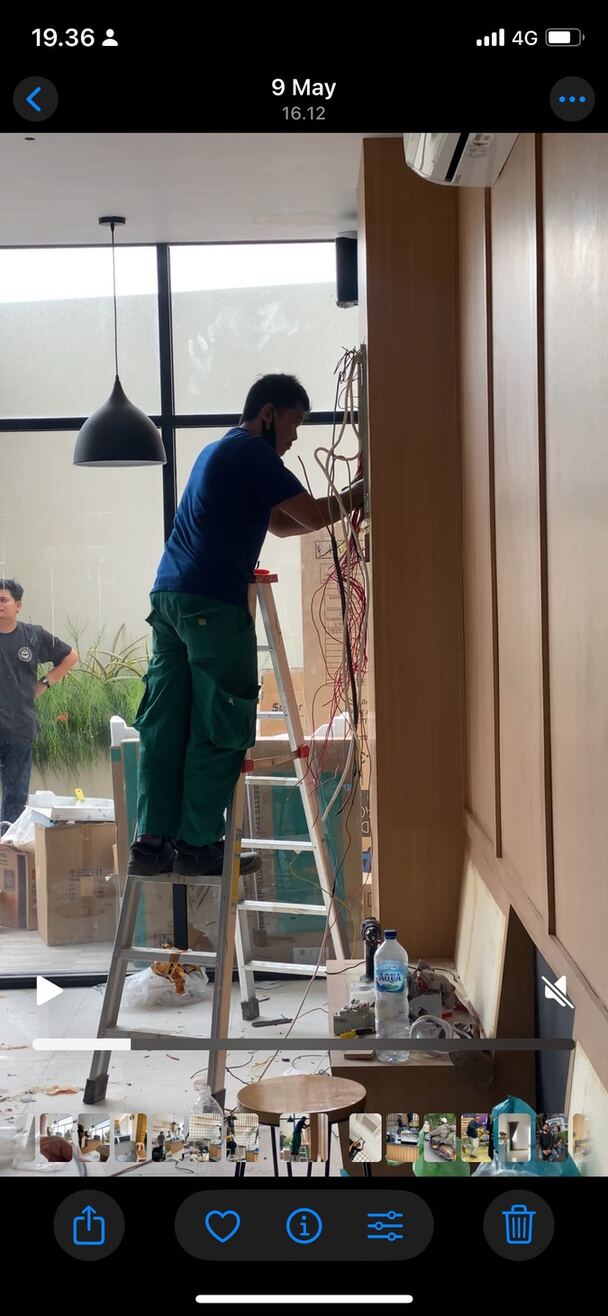 Pekerja memasang panel kayu interior menggunakan tangga