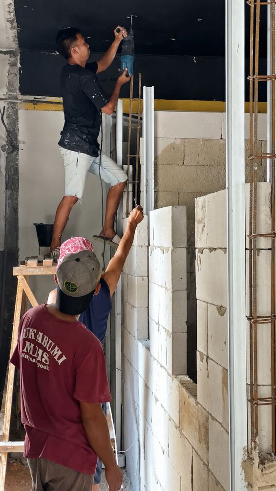 Pekerja memasang panel dinding di lokasi proyek
